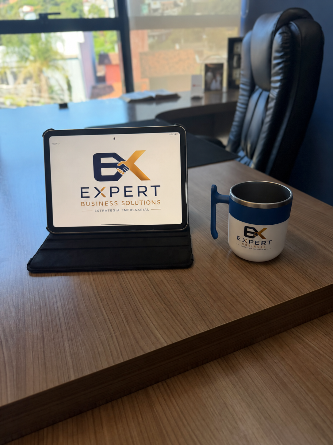 Tablet e caneca com a marca Expert Business Solutions sobre a mesa do escritório